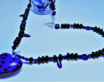 Ladies glass beaded necklace in cobalt blue and black beads with a glass puffed heart pendant and heart shaped sterling silver toggle; Heart