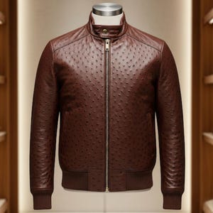 May include: A brown leather jacket with a textured surface and a bomber-style design. The jacket features a stand-up collar, a full-length zipper, and ribbed cuffs and hem. The jacket is displayed on a mannequin.