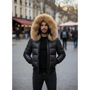 Puede incluir: Chaqueta acolchada negra con capucha forrada de piel marrón. La chaqueta tiene un estilo bomber con dobladillo y puños acanalados. La persona de la imagen lleva un jersey negro y vaqueros oscuros.