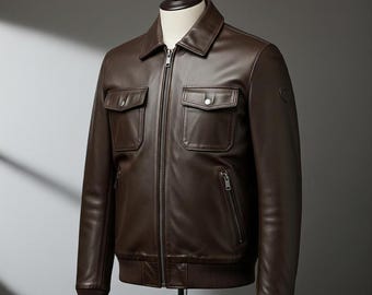 May include: A brown leather jacket with a collared neckline, two chest pockets, and two side pockets. The jacket has a zip-up front and ribbed cuffs and hem. The jacket is displayed on a mannequin.
