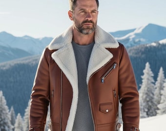 May include: A brown leather jacket with a white shearling collar and lining. The jacket features a diagonal zipper, a small pocket, and buckled cuffs. The background shows snow-covered mountains and trees.