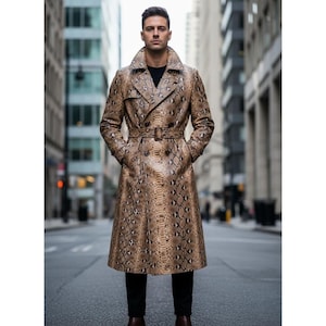 Puede incluir: Un abrigo largo tipo gabardina de doble botonadura con un estampado de piel de serpiente en tonos marrón y beige. El abrigo tiene un cinturón en la cintura y un cuello ancho. La persona lleva pantalones negros y zapatos marrones.