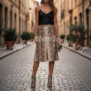 May include: A woman wearing a black camisole top and a snakeskin-print midi skirt with a front slit. Matching snakeskin-print ankle boots and a clutch complete the outfit. The image is taken on a cobblestone street.