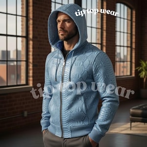 Puede incluir: Sudadera con capucha azul claro con cremallera y estampado de piel de serpiente. La sudadera tiene capucha con cordón, bolsillos delanteros y puños y dobladillo de canalé. El texto "tip top wear" está impreso en la parte superior e inferior de la imagen.