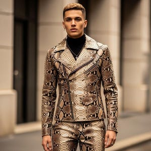 Può includere: Completo giacca e pantaloni con motivo a pelle di serpente. La giacca, in stile biker, presenta un colletto a revers e una cerniera asimmetrica. I pantaloni sono abbinati al motivo della giacca. L'outfit è nei toni del marrone e beige.