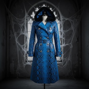 Może przedstawiać: Niebieski płaszcz typu trench w wzór skóry węża z kapturem podszytym czarnym futrem. Dwurzędowy płaszcz posiada srebrne guziki, pasek i klasyczny krój płaszcza. Płaszcz jest prezentowany na manekinie.