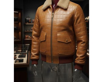 May include: A brown leather bomber jacket with a faux fur collar. The jacket features a crocodile skin texture, two front pockets, and a ribbed hem and cuffs. The jacket is displayed on a mannequin.