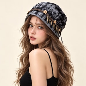May include: A slouchy beanie in a black and white tie-dye pattern featuring a brown braided cord trim. The hat is decorated with small wooden flower-shaped beads and dangling metallic cone-shaped charms attached along the front edge.