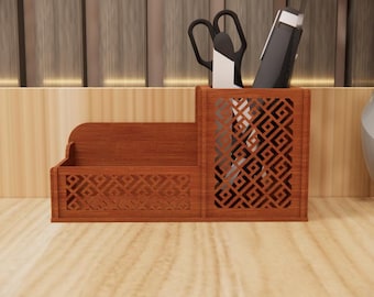 Puede incluir: Organizador de escritorio de madera con diseño geométrico calado. Tiene dos secciones: una bandeja pequeña y un compartimento más alto que contiene tijeras y un bolígrafo. La madera tiene un tono marrón rojizo cálido.