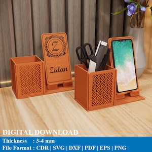 Peut inclure: Organisateur de bureau en bois avec un support pour téléphone, un porte-stylo et un support gravé du nom "Zidan". L'organisateur présente un motif géométrique et contient un téléphone, des ciseaux et des stylos. L'épaisseur est de 3-4 mm.