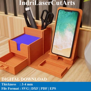 Könnte beinhalten: Ein Schreibtisch-Organizer aus hellem Holz mit Handyhalterung, Stifthalter und kleiner Schublade. Der Organizer ist aus hellbraunem Holz gefertigt und hat einen blauen Notizblock. Der Text "IndriLaserCutArts" und "DIGITALER DOWNLOAD" ist ebenfalls enthalten.