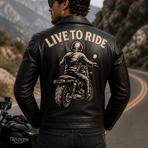 Könnte beinhalten: Schwarze Leder-Motorradjacke mit dem Text "LIVE TO RIDE" und einer Motorradgrafik auf dem Rücken. Die Jacke wird mit schwarzen Jeans getragen. Im Vordergrund ist ein schwarzes Triumph-Motorrad zu sehen.