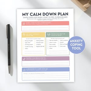 May include: A white paper worksheet titled MY CALM DOWN PLAN with sections for identifying warning signs, coping strategies, support contacts, and reminders. The document features pastel-coloured boxes and a black pen sits to the left side.