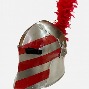 May include: A silver-colored medieval helmet with red stripes and a red plume. The helmet has a visor with a narrow eye slit and a chain detail. The red stripes are painted across the front and sides of the helmet.