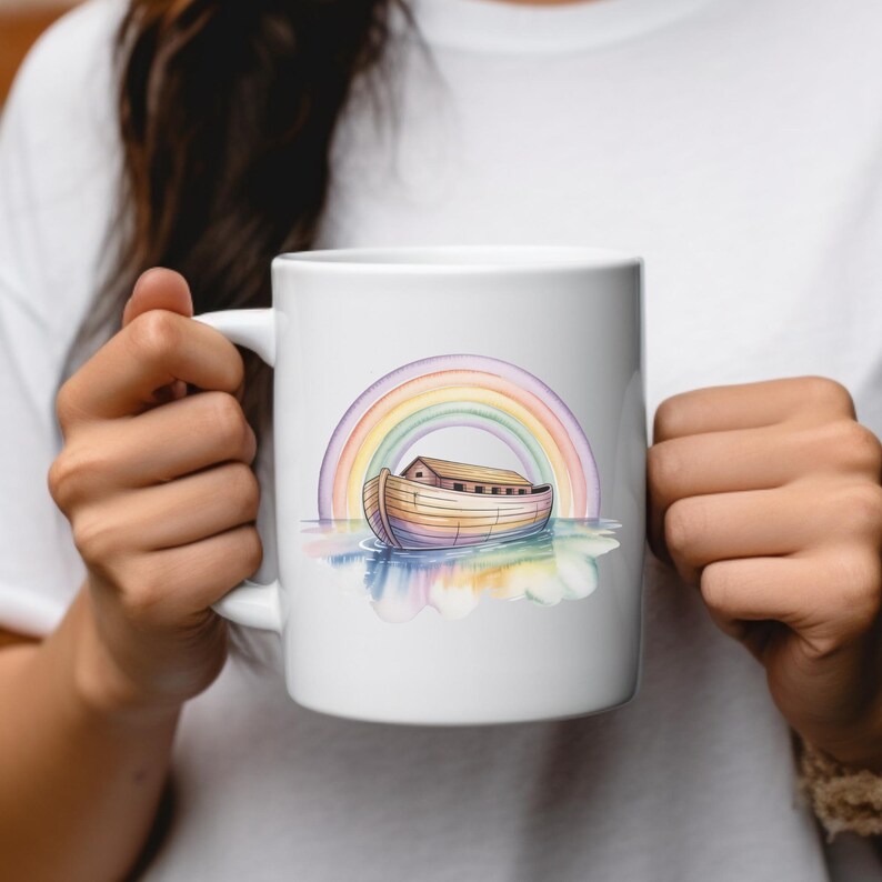 Puede incluir: Taza de cer&aacute;mica blanca con una ilustraci&oacute;n de acuarela del Arca de No&eacute; bajo un arco&iacute;ris. El arca es de color marr&oacute;n claro con una peque&ntilde;a estructura de madera. El arco&iacute;ris tiene colores pastel.