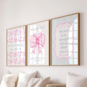 Könnte beinhalten: Drei gerahmte Wandbilder mit hellen Holzrahmen. Das linke Bild zeigt rosa Blumenmuster und den Text His Mercies Are New Every Morning. Das mittlere Bild zeigt eine rosa Schleife und Proverbs 31:25. Das rechte Bild hat blaue Blumenmuster, einen rosa Rand und The Lord is my strength and my shield Psalm 28:7.
