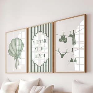 May include: Three framed art prints with a beach theme. The left print features a green seashell with a bow. The center print has the text "MEET ME AT THE BEACH". The right print shows beach attire hanging on a clothesline.