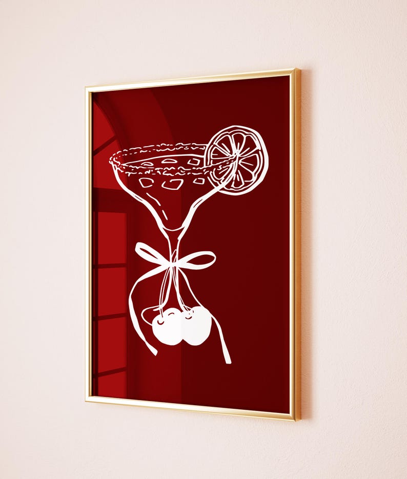 May include: A framed art print featuring a white line drawing of a margarita cocktail with a lime slice and cherries on a deep red background. The print is in a gold frame.