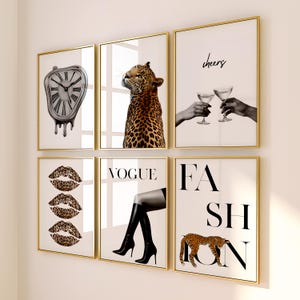 May include: Six framed wall art prints with gold frames. The prints feature a melting clock, a leopard, hands toasting with glasses, leopard print lips, the word "Vogue" with a leg in a boot, and the word "Fashion" with a leopard.