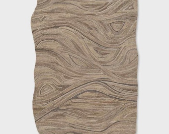 May include: A large, irregularly shaped rug with a swirling, wood-grain pattern in shades of beige, brown, and gray. The rug's edges are uneven, adding to its organic aesthetic. The design resembles the cross-section of a tree trunk.