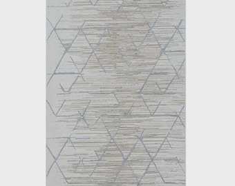 May include: A rectangular area rug featuring a light gray and beige color palette. The surface displays a repeating geometric pattern of thin, angular lines in a soft blue-gray tone, layered over a textured, horizontal, striated background.