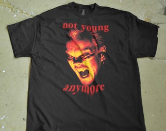 May include: Black t-shirt with a red and yellow graphic of a screaming face. The words "not young anymore" are printed above and below the face in red. The shirt is laid flat on a concrete surface.