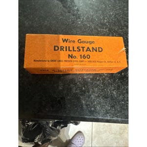 May include: An orange Wire Gauge DRILLSTAND No. 160 box. The box is made in the USA by GREAT LAKES PRESSED STEEL CORP. The text on the box reads "FOR A SPEEDY SELECTION OF THE SIZE OF DRILL NEEDED."