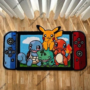 Peut inclure: Un tapis rectangulaire conçu pour ressembler à une console de jeu vidéo, avec des côtés de manette bleus et rouges. Le centre affiche un fond de ciel bleu avec les personnages de dessins animés Pikachu, Squirtle, Bulbasaur et Charmander. Le tapis est en matière douce.