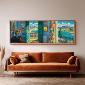 Puede incluir: Una pintura panorámica enmarcada representa una vibrante escena costera con puertas verdes abiertas y un balcón con vistas al mar. La obra de arte presenta un interior azul con una mesa, una silla y cortinas coloridas. Debajo hay un sofá color óxido con cojines.