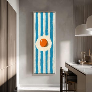 May include: A vertical rectangular wall art piece featuring a central fried egg motif with a bright orange yolk and white albumen, set against a background of alternating vertical blue and white painted stripes with visible brushstroke textures.