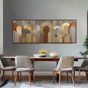 Puede incluir: Una obra de arte en lienzo rectangular enmarcada con un diseño abstracto de formas de arco en tonos dorados, marrones y grises. La obra de arte cuelga sobre una mesa de comedor de madera con cuatro sillas.