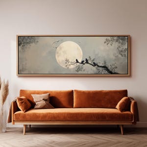 May include: A rectangular wall art print in a light wood frame featuring a large, pale full moon against a soft, cloudy sky. Several dark birds are perched on a gnarled tree branch extending from the right side, with a few birds flying.