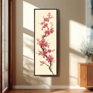 Può includere: Un'opera d'arte verticale incorniciata con un ramo di fiori di ciliegio rosa su uno sfondo color crema. I fiori sono in varie tonalità di rosa e il ramo è marrone scuro. La cornice è di colore marrone scuro.