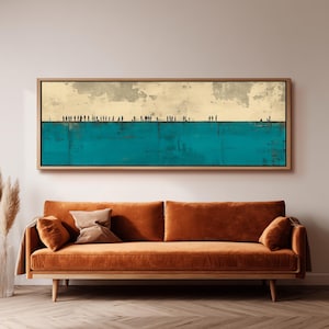 May include: Abstract art print in a wooden frame. The artwork features a teal blue lower section and a beige upper section with a textured appearance. Silhouetted figures are positioned along the top edge. The artwork hangs above a rust-colored sofa.