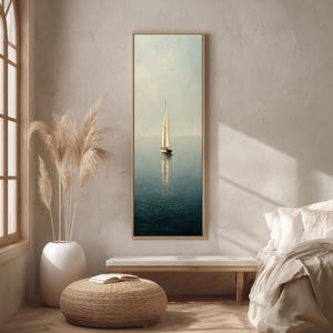 Peut inclure: Impression sur toile verticale encadrée d'un voilier sur une eau calme. L'œuvre présente un voilier beige avec un grand mât, reflété dans l'eau bleu-vert. Le ciel est bleu pâle et le cadre est marron clair.
