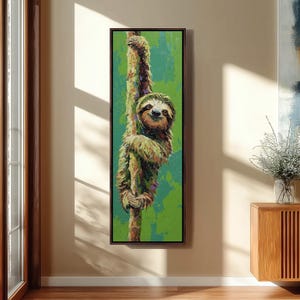 以下が含まれることがあります： 木にぶら下がっている笑顔のナマケモノが描かれた、額入りの縦型キャンバスアートプリント。ナマケモノは、テクスチャ加工された緑色の背景に対して、緑と茶色の色合いで描かれています。このアートワークは絵画風のスタイルです。