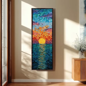 May include: A mosaic artwork showing a sunset over the sea. The artwork features a yellow sun, orange and red sky, and blue water. The mosaic is framed in a dark brown frame and is displayed on a beige wall.