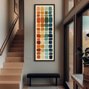 Può includere: Opera d'arte incorniciata verticalmente con una serie di pennellate rettangolari colorate. L'opera presenta una tavolozza di toni caldi e freddi, tra cui arancione, rosso, giallo, verde e blu. L'opera è esposta in un interno ben illuminato.