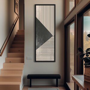 May include: A tall, rectangular framed wall art piece featuring a geometric design. The artwork displays a large, dark charcoal gray triangle set against a background of fine, alternating vertical and horizontal black lines on a cream-colored base.