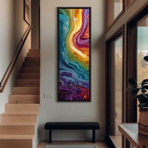 May include: A framed abstract art piece with a vibrant, flowing design. The artwork features a blend of colors, including yellow, orange, red, purple, blue, and green, creating a dynamic and visually appealing composition. The piece is displayed on a white wall.