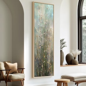 May include: A tall, vertical rectangular wall art piece featuring an impressionistic painting of wildflowers and tall grasses in soft shades of sage green, pale blue, cream, and muted yellow, enclosed in a light-toned wooden frame.