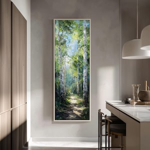 May include: Vertical framed painting of a forest path. The artwork depicts tall birch trees with white bark and green foliage, bathed in sunlight. The path leads into the distance, creating a sense of depth and tranquility. The painting is in a white frame.