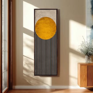 Puede incluir: Arte mural abstracto con un gran círculo amarillo sobre rayas verticales en blanco y negro. La obra de arte está enmarcada en un marco rectangular marrón oscuro y cuelga de una pared beige. La pieza de arte añade un toque moderno a cualquier habitación.