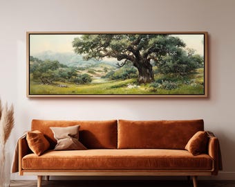 Può includere: Un dipinto paesaggistico panoramico in una cornice di legno chiaro raffigurante una grande quercia nodosa in un prato erboso con colline e montagne in lontananza sotto un cielo tenue. L'opera è esposta sopra un lungo divano in velluto arancione.