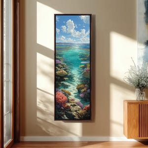 Puede incluir: Una obra de arte vertical enmarcada que representa una escena submarina. La pintura muestra un vibrante arrecife de coral con corales y peces coloridos, bajo un mar turquesa claro y un cielo azul con nubes blancas esponjosas. La obra de arte se exhibe en una pared beige.