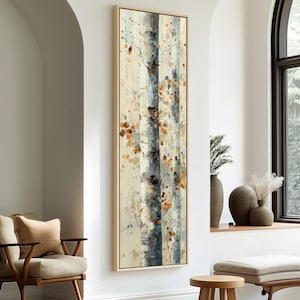 Pode incluir: Impressão de arte emoldurada verticalmente com bétulas. A obra de arte utiliza uma paleta neutra de bege, cinza e azul, com folhas laranja e marrons. A pintura é apresentada em uma moldura de madeira clara, adequada para decoração.