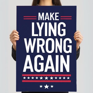 Może przedstawiać: Granatowy plakat z napisem "MAKE LYING WRONG AGAIN" dużymi białymi literami. Plakat ma czerwone paski i gwiazdy, przypominające patriotyczny motyw. Plakat jest trzymany przez osobę.