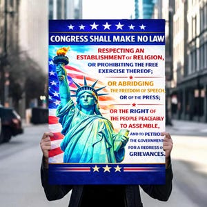 Puede incluir: Un póster con la Estatua de la Libertad y la bandera estadounidense de fondo. El póster incluye el texto de la Primera Enmienda de la Constitución de EE. UU., con un borde azul y rojo y estrellas.