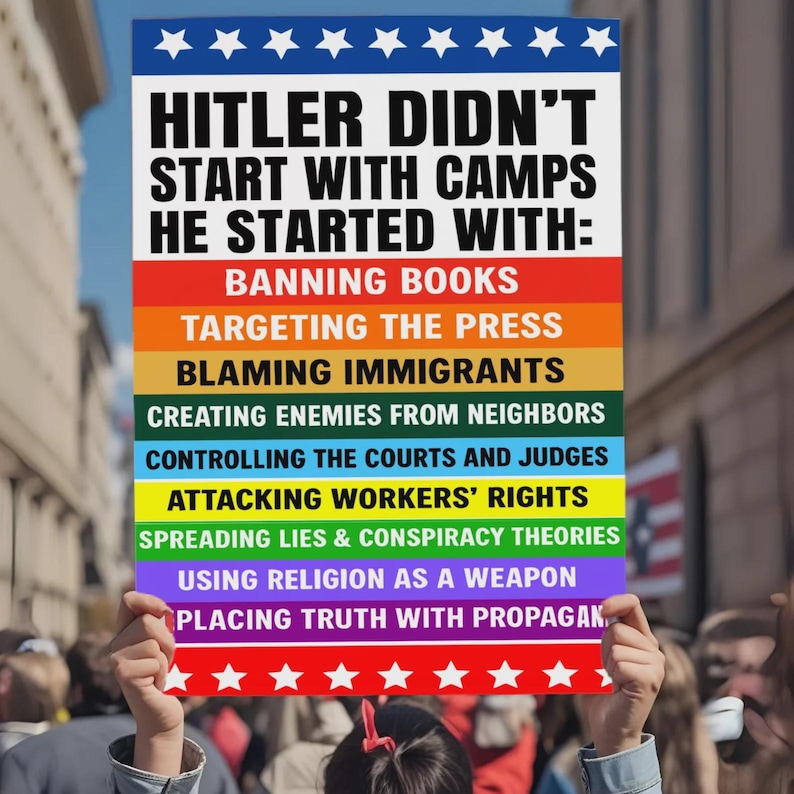 Puede incluir: Un cartel sostenido por una persona en una multitud. El texto dice: "HITLER DIDN'T START WITH CAMPS HE STARTED WITH:" seguido de una lista de acciones en bloques de colores del arco&iacute;ris. La parte superior es azul con estrellas blancas.