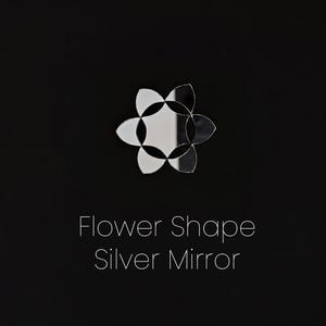 Puede incluir: Un espejo plateado con forma de flor, sobre un fondo negro. El texto "Flower Shape Silver Mirror" se muestra en blanco, centrado debajo de la flor.